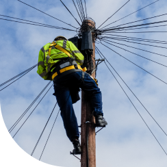 Man climbing telephone pole with many wires over head